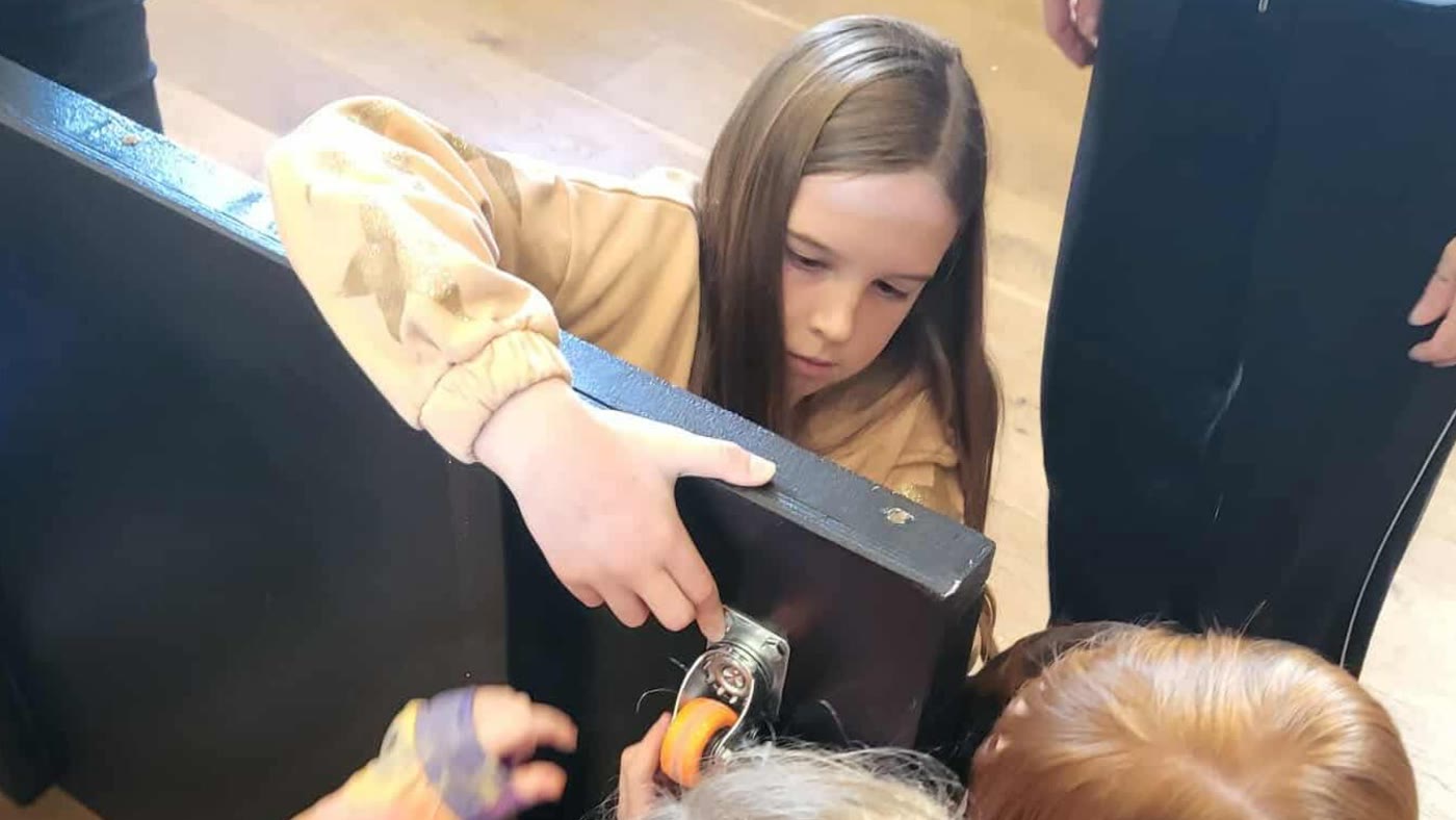 A pupil fitting a wheel with a socket wrench